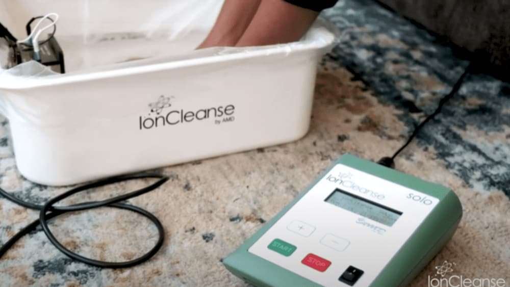 IonCleanse foot bath therapy in use, with a user’s foot submerged in the detoxifying water, showcasing the IonCleanse device and its control panel.