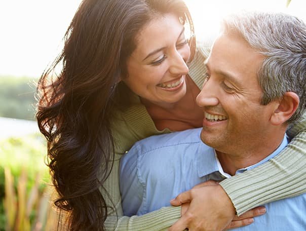 Couple smiling and embracing outdoors, symbolizing confidence and well-being in sexual health treatment.