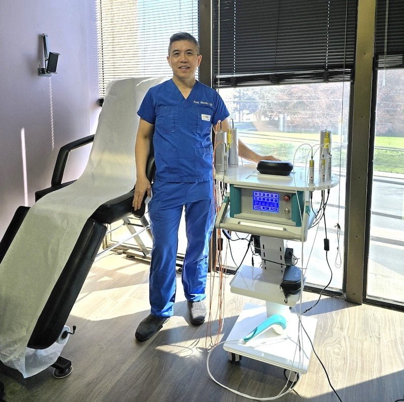 Medical professional in blue scrubs standing beside the Weberneedle Endolaser device, showcasing low-level laser therapy equipment in a clinical setting.